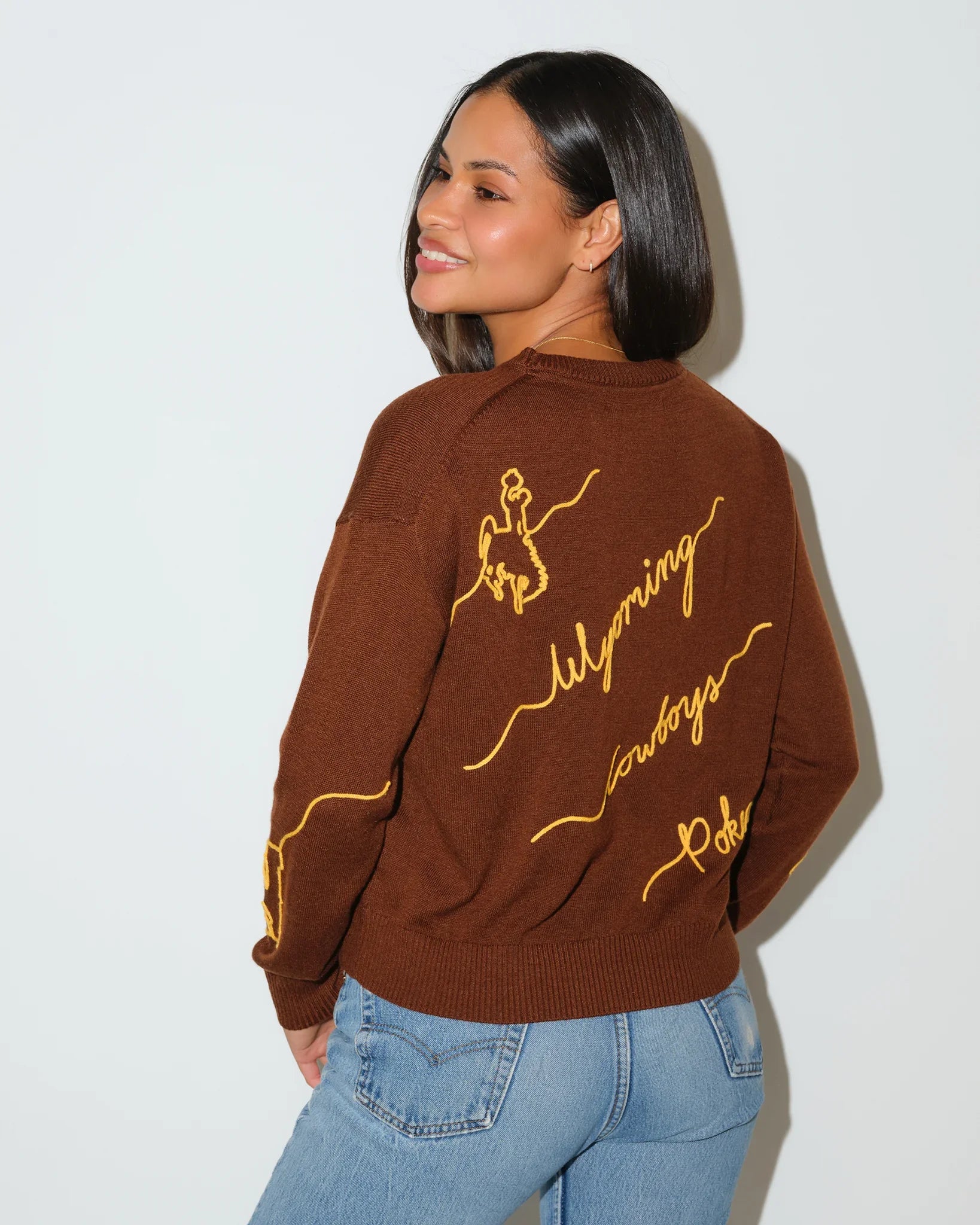 Brown Wyoming Cowboys Love Letter Sweater with gold cursive "Wyoming Cowboys" script embroidery across the front and sleeve.