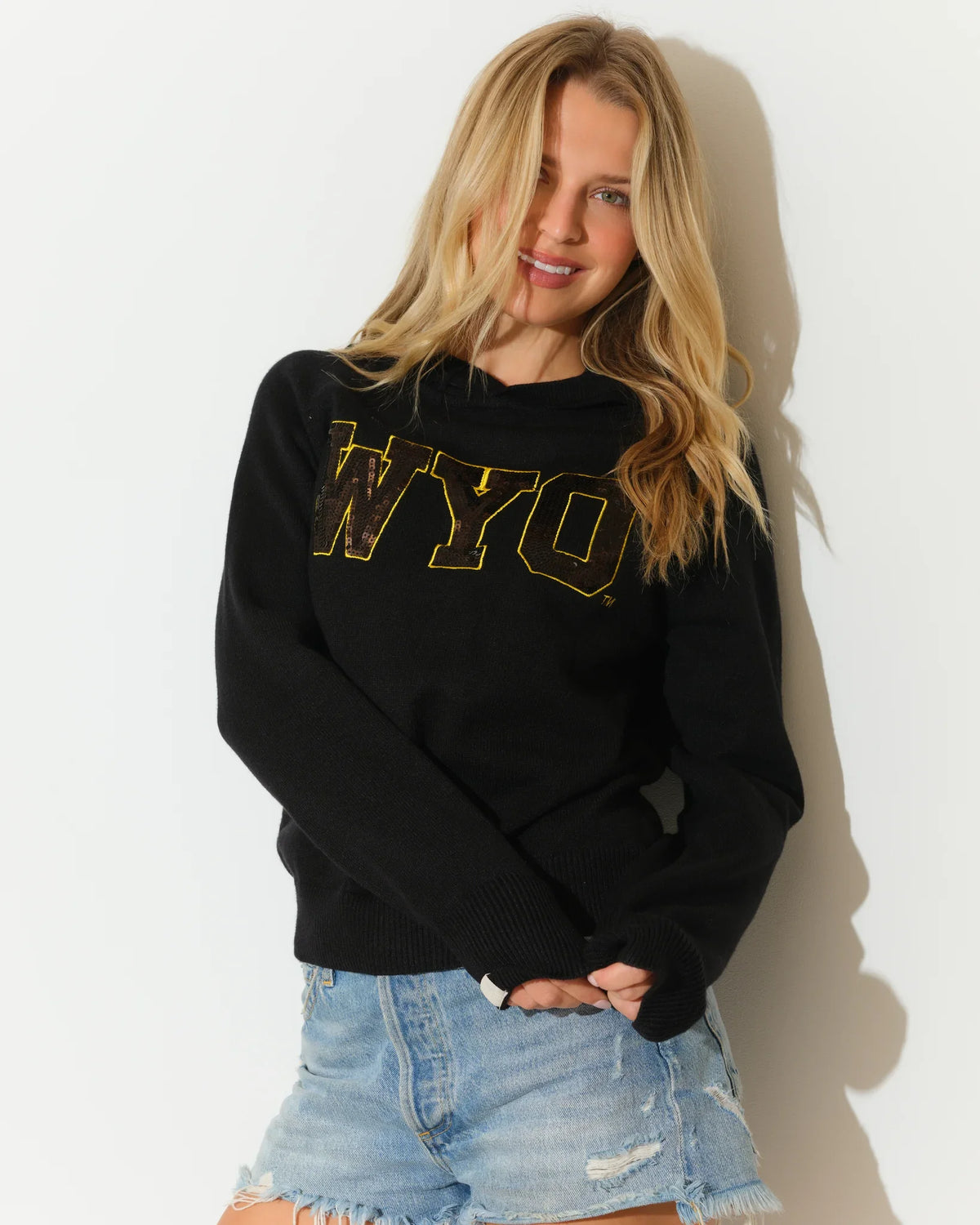 Black Wyoming Cowboys sequin knit hoodie featuring gold sequin "WYO" lettering on the chest, modeled with a relaxed fit.