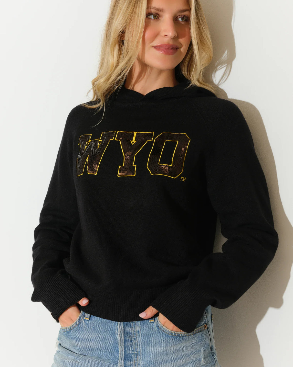 Black Wyoming Cowboys sequin knit hoodie featuring gold sequin "WYO" lettering on the chest, modeled with a relaxed fit.