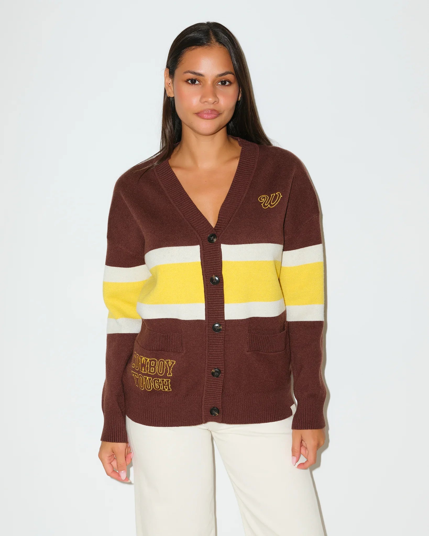 Brown Wyoming Cowboys oversized cardigan with yellow and white chest stripes, gold embroidered logo, and "Wyoming Cowboys" text on the hem.
