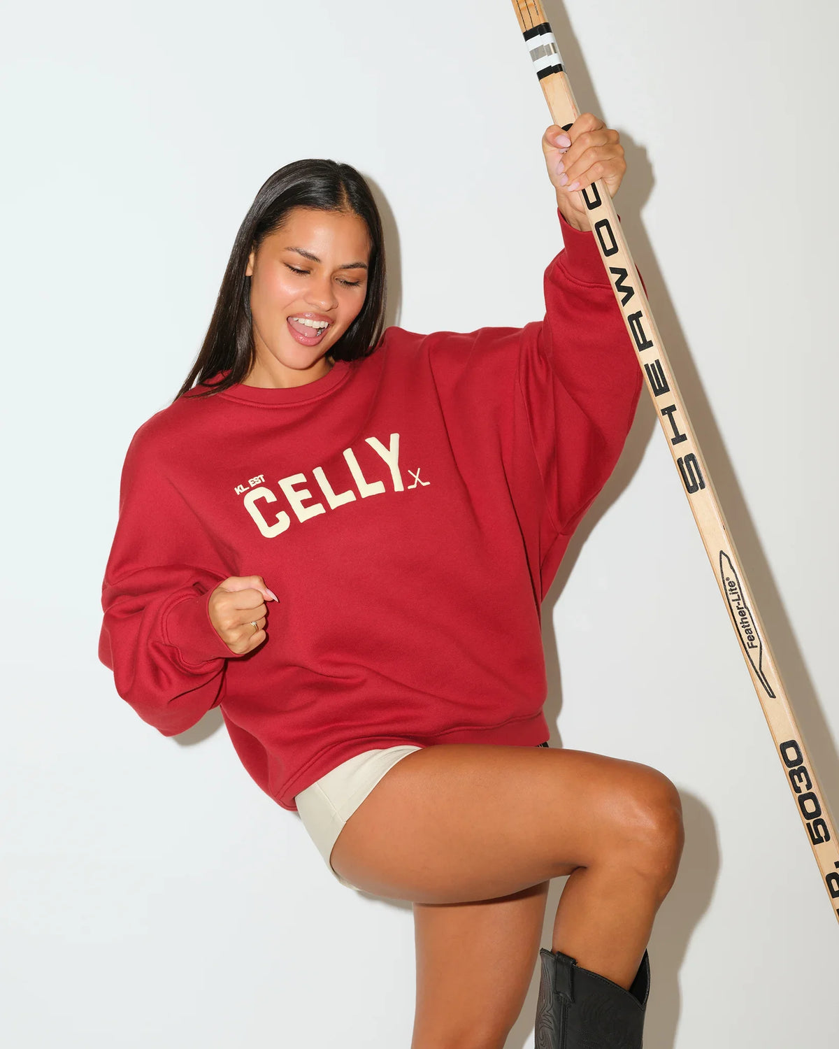 Red KadyLuxe balloon sleeve crew sweatshirt with gold "CELLY" graphic lettering on the chest, featuring relaxed fit and puffed sleeves.