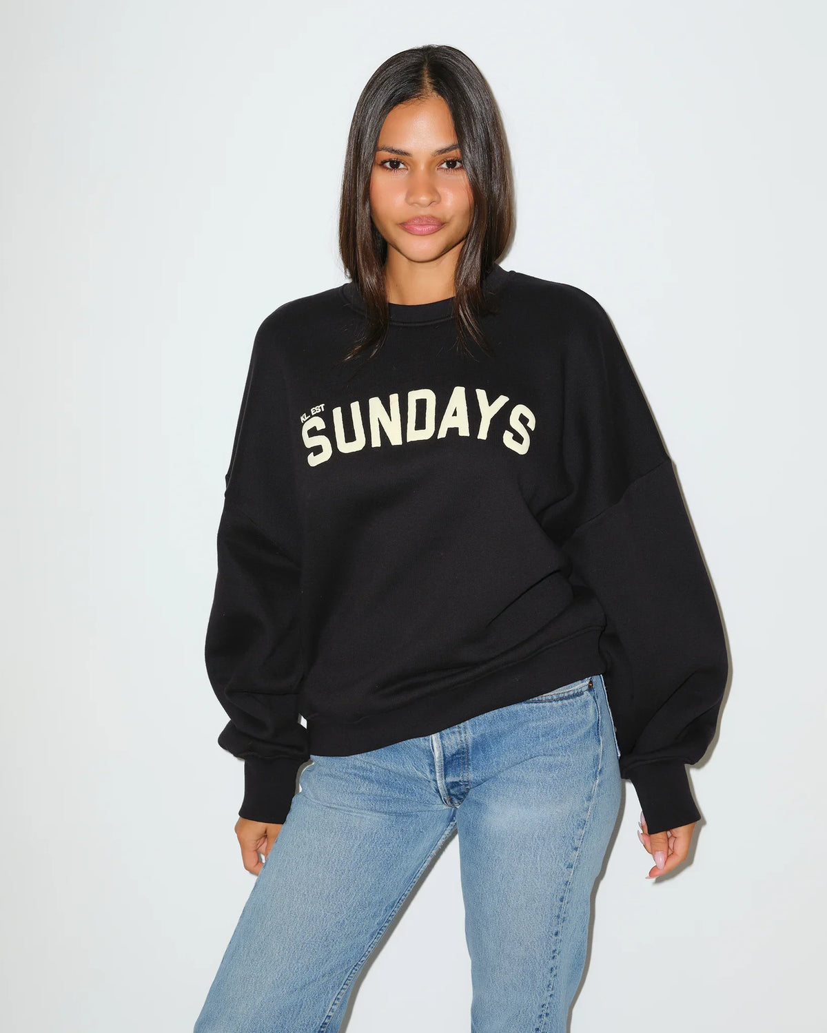Black KadyLuxe balloon sleeve crew sweatshirt with cream "SUNDAYS" graphic lettering across the chest, featuring oversized dropped shoulders.