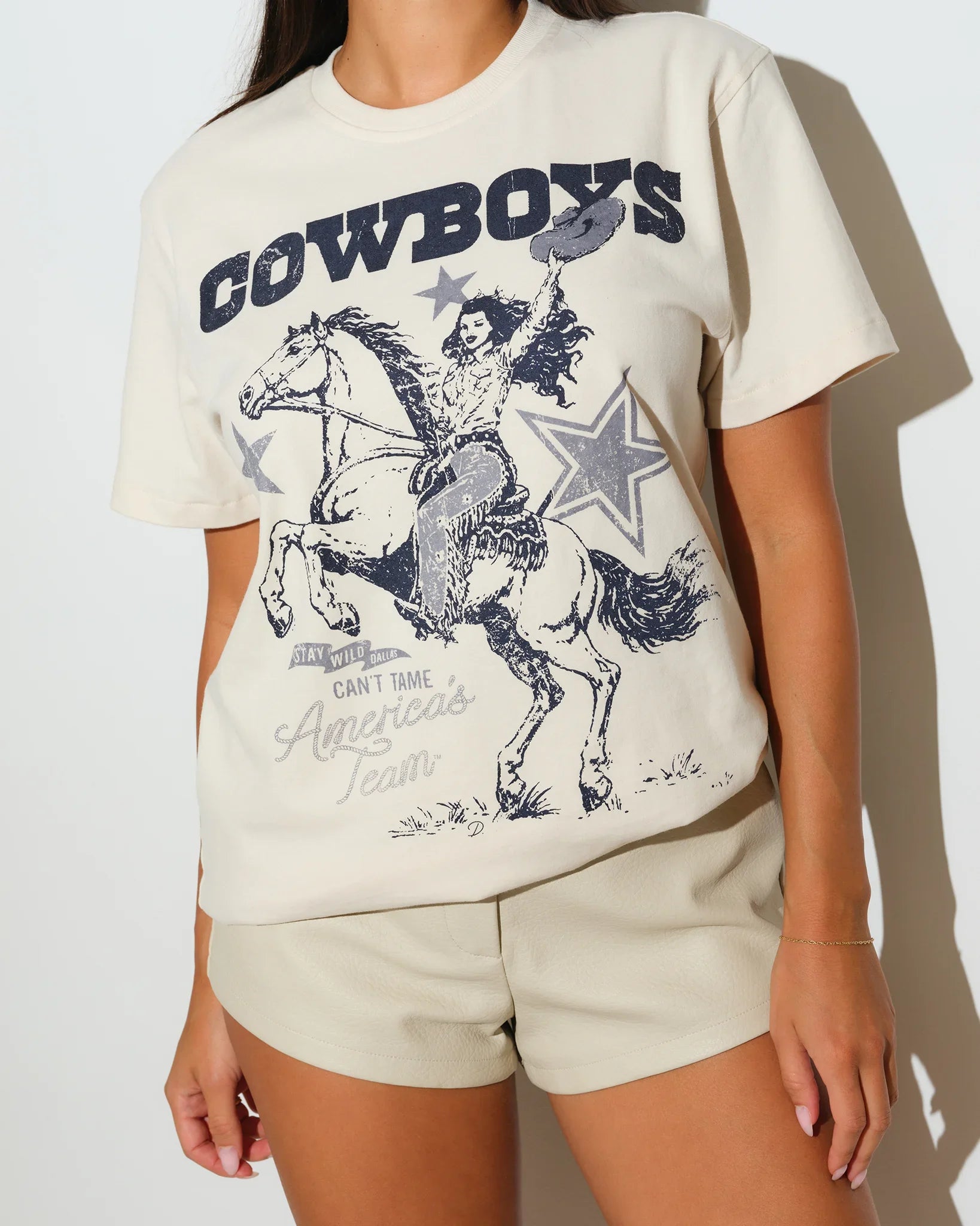 Bone Dallas Cowboys Game Changer Tee featuring a navy graphic of a cowboy on horseback with "Cowboys" text on the chest.