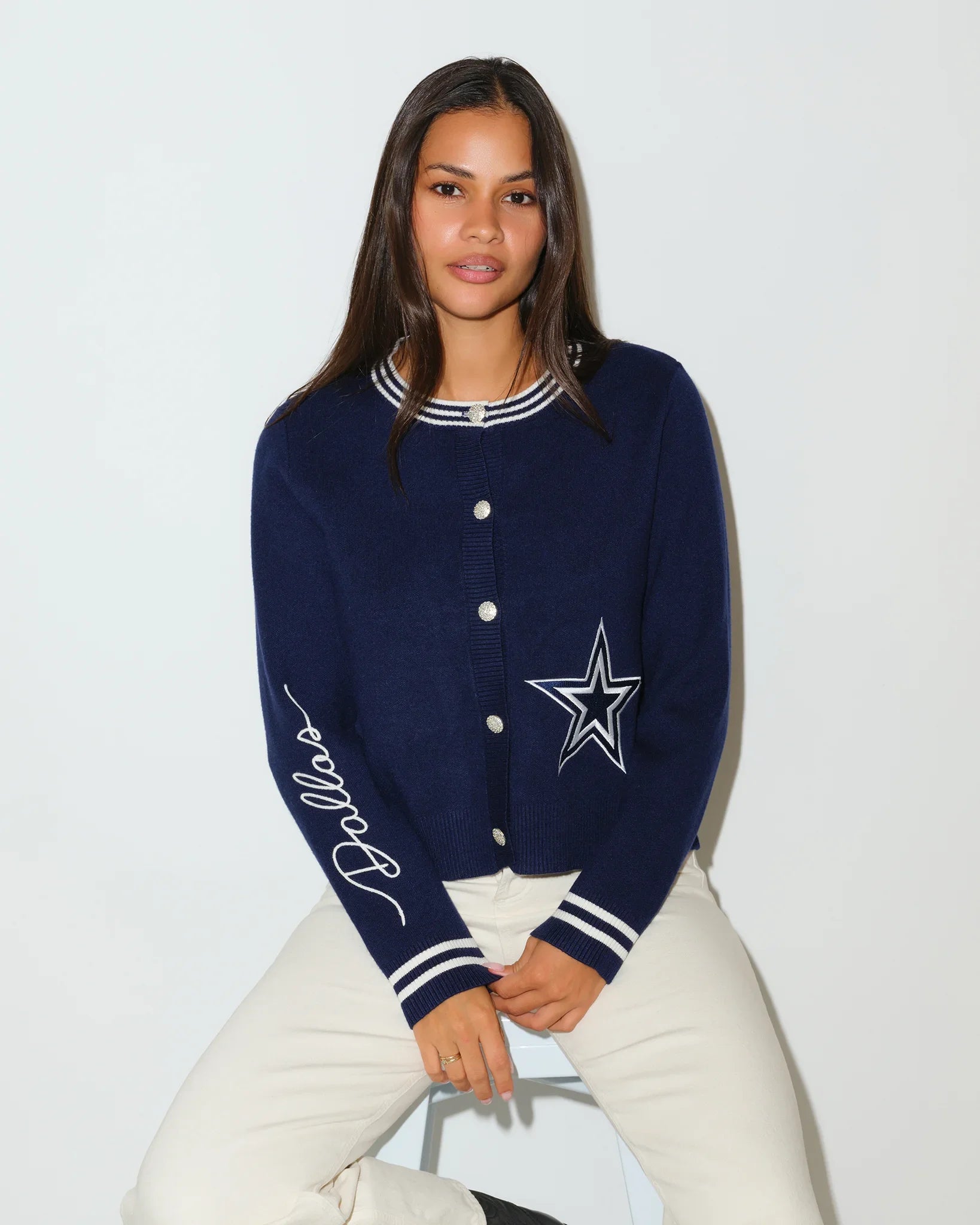 Navy Dallas Cowboys mini cardigan with silver star logo on chest, striped trim, and "Cowboys" script on sleeve, styled on a seated female model.