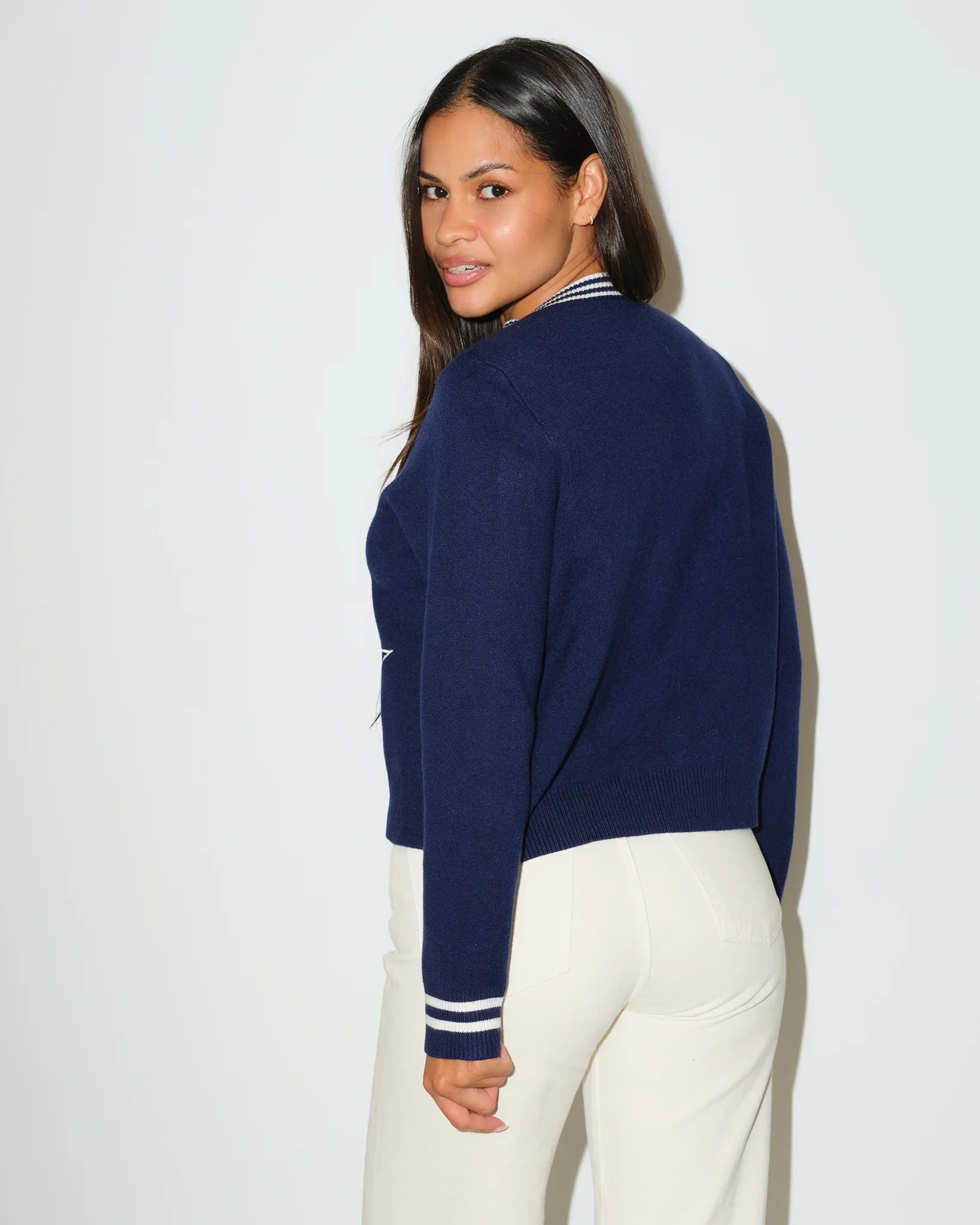 Navy Dallas Cowboys mini cardigan with silver star logo on chest, striped trim, and "Cowboys" script on sleeve, styled on a seated female model.