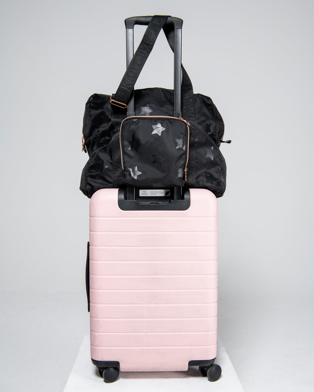 KADYLUXE® packable travel bag in black star print shown on luggage.
